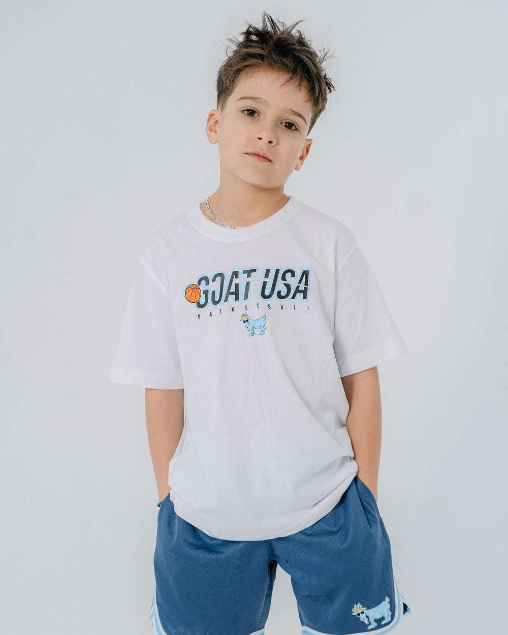 Kid wearing white shirt with basketball that goes through the wording "GOAT USA"