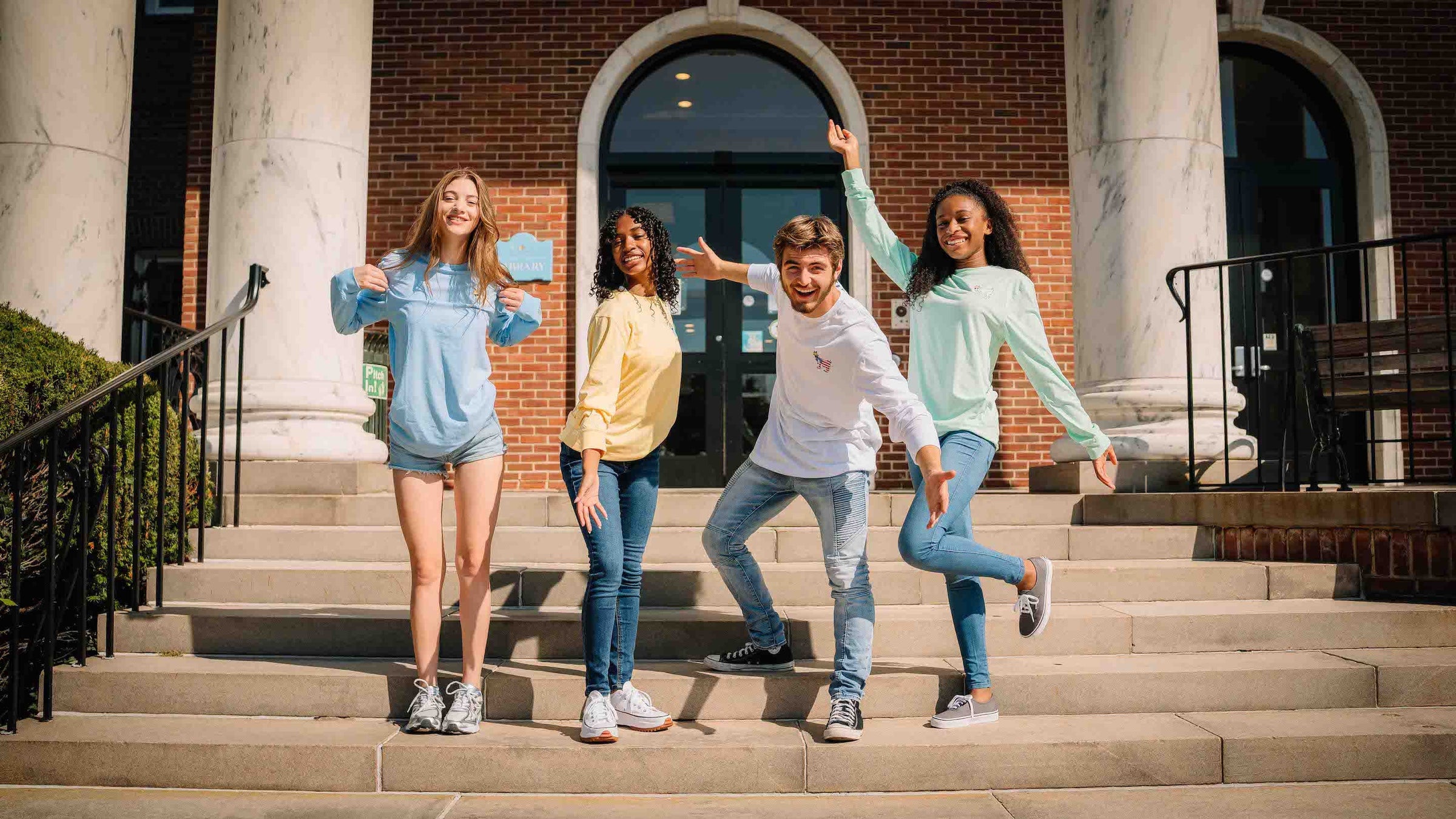 Four models wearing GOAT USA in front of a library