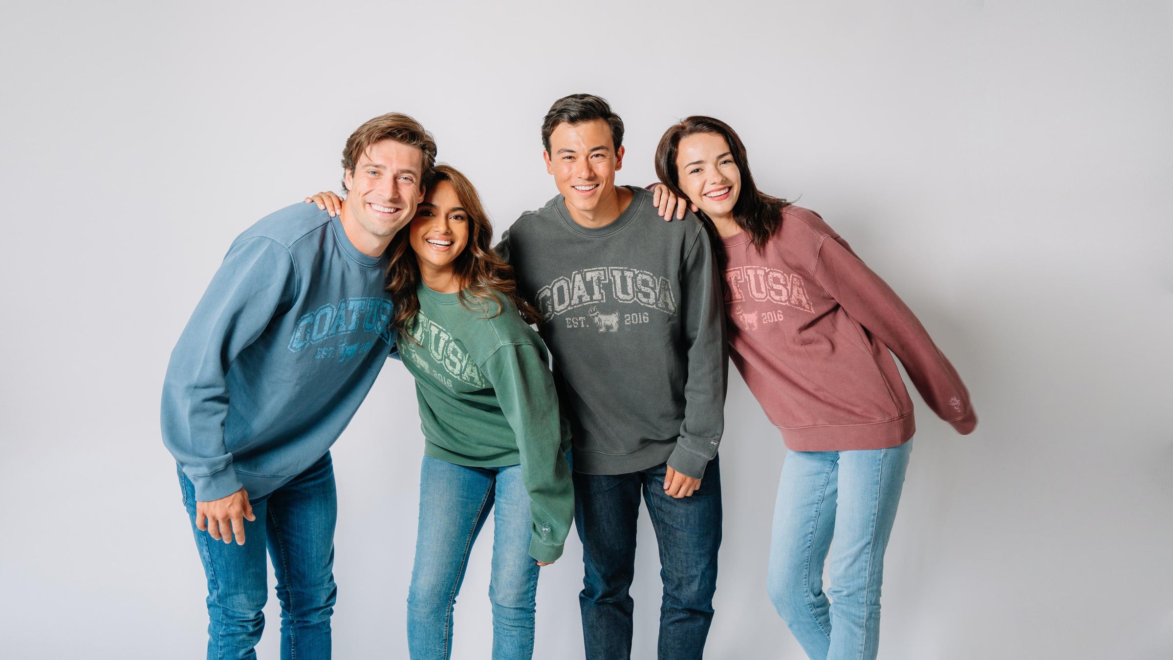 Four people standing side by side wearing different color sweatshirts