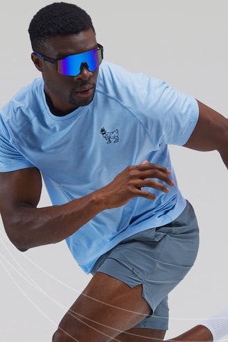 Person wearing a light blue t-shirt and gray shorts running on a white background