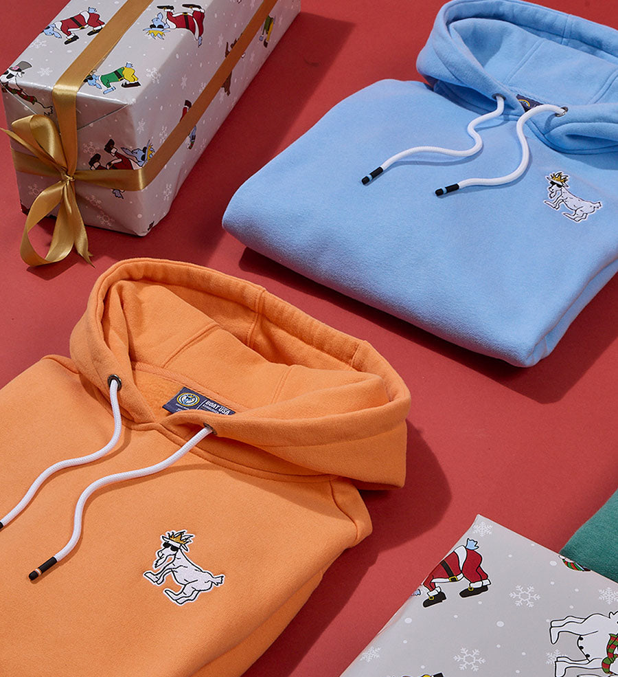 Two hoodies, one orange and one blue, on a red surface with gift-wrapped boxes.