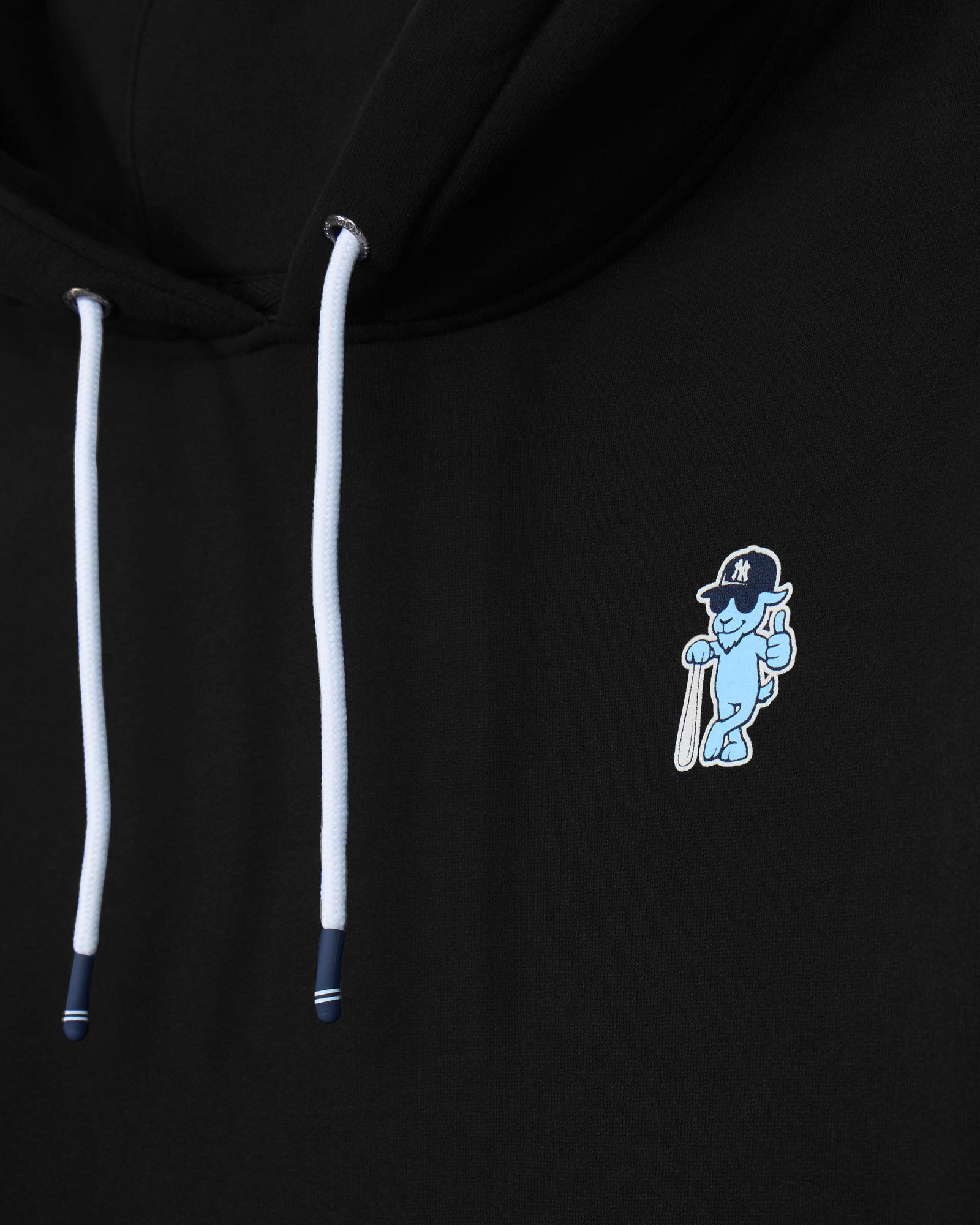 Close-up of a black hoodie featuring white drawstrings and a small light blue embroidered mascot logo on the chest.