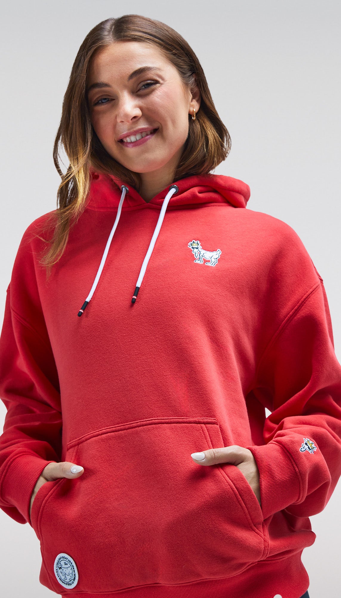 Person wearing a red hoodie with a small logo on a plain background