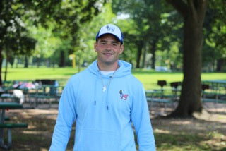 Man in park wearing sweatshirt and hat