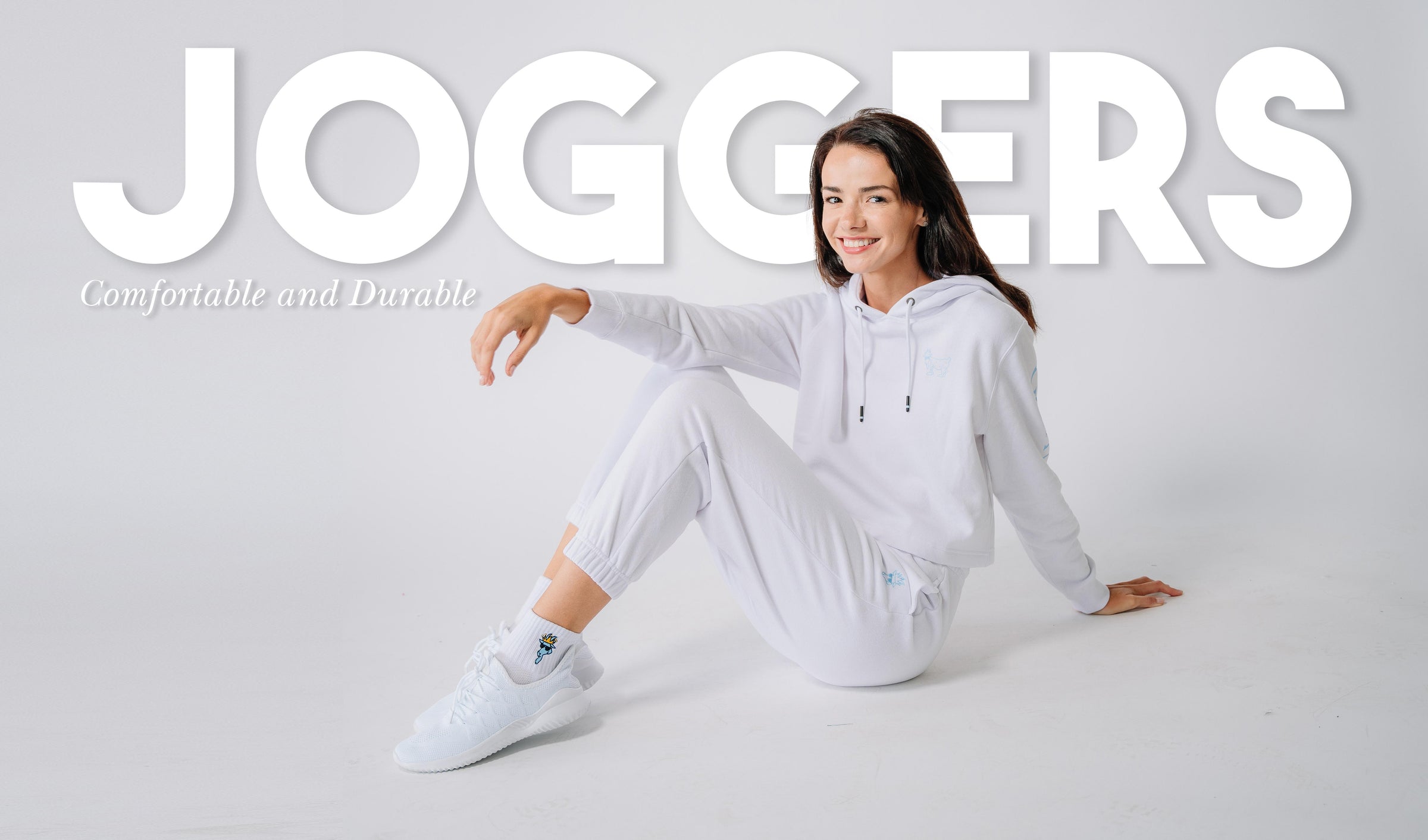 Image with model sitting on ground wearing white joggers linked to Joggers collection