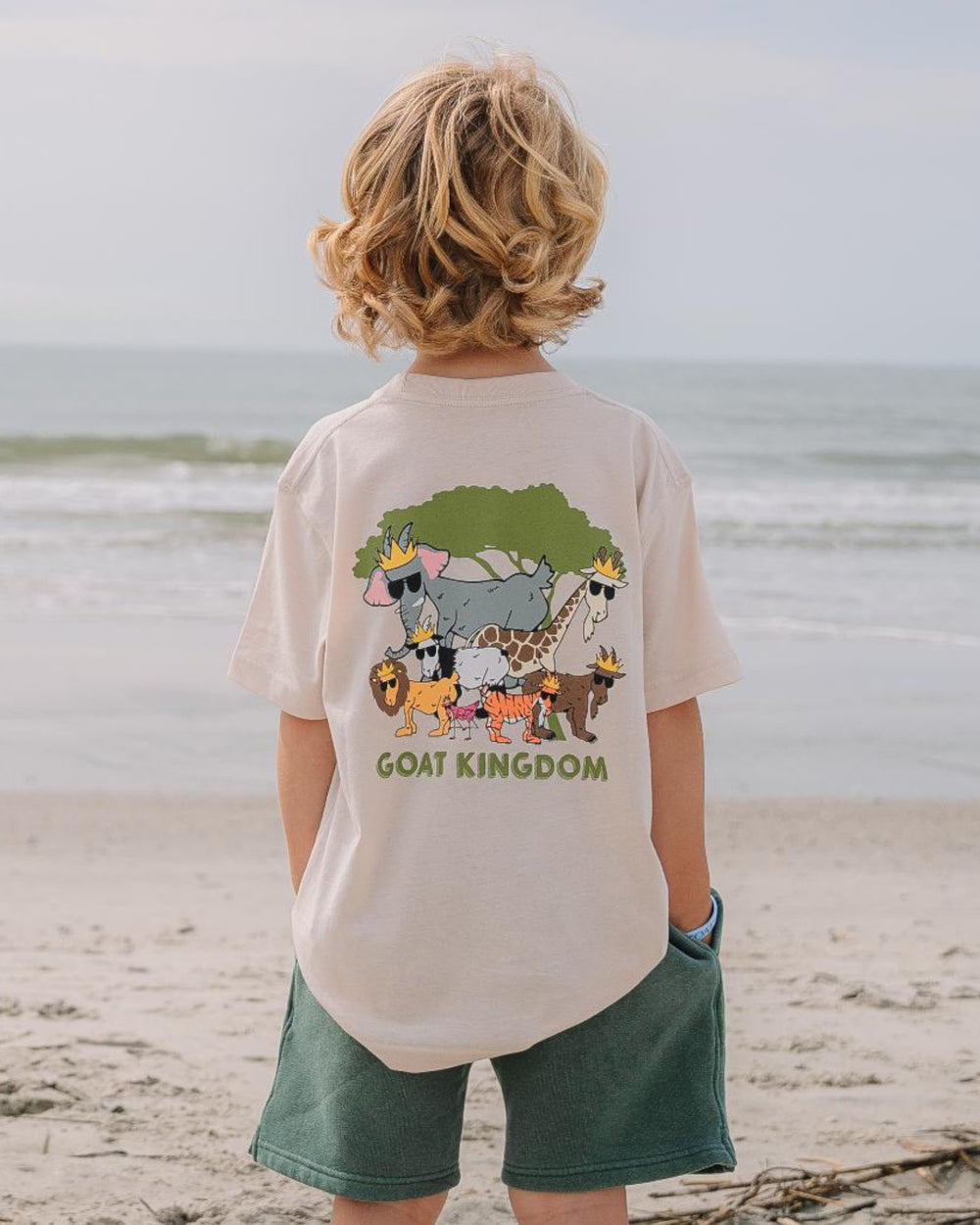 Kid on the beach looking at the ocean with hands in his pockets