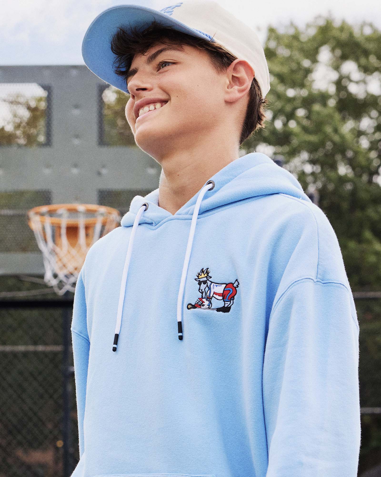 Person wearing a light blue hoodie with a small graphic on a basketball court