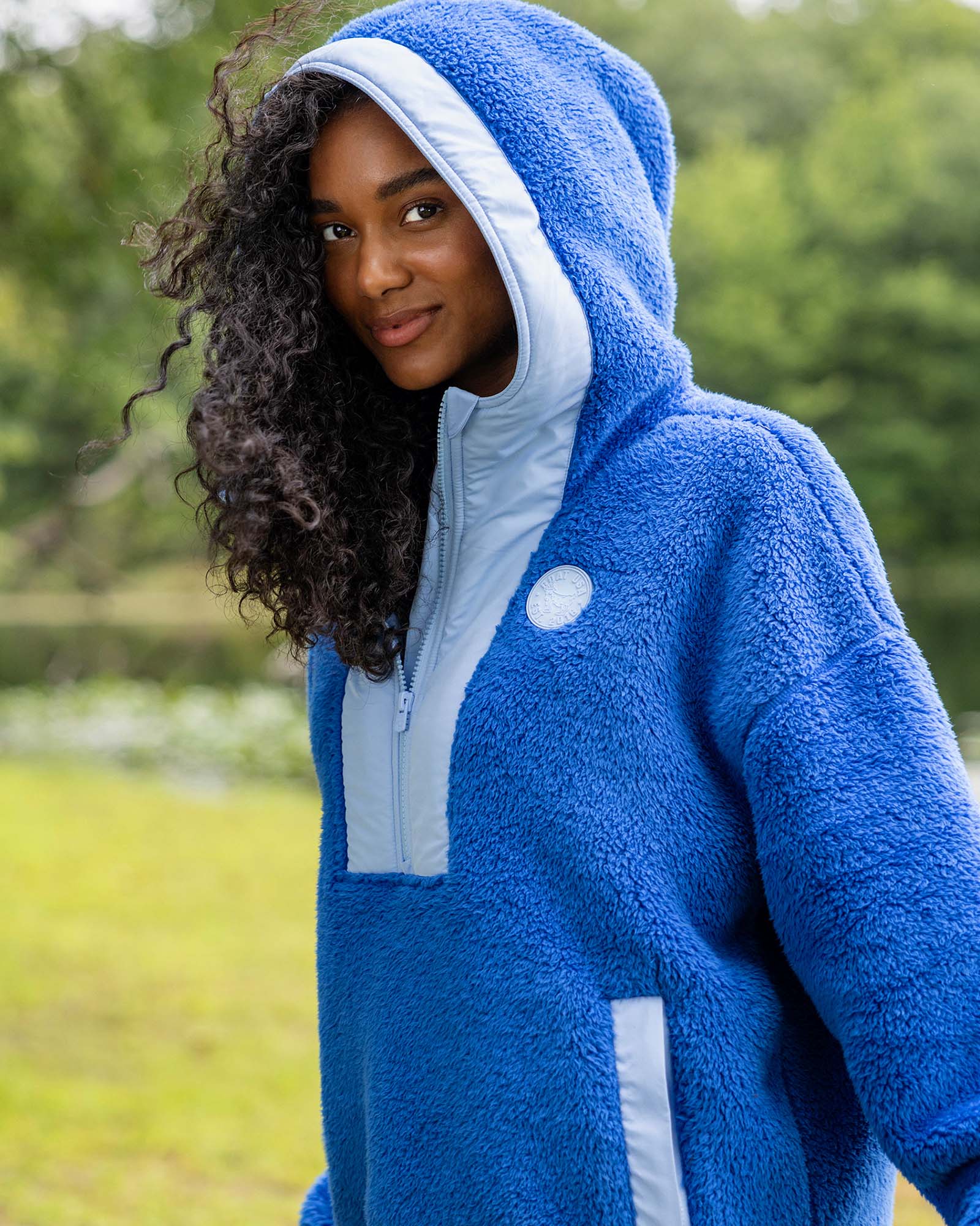 Person wearing a blue fleece hoodie with a hood in an outdoor setting