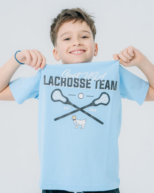 Kid holding up blue Lacrosse Team t-shirt