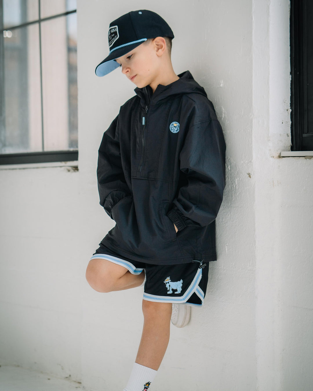 Kid wearing black mesh shorts with blue and white waistband#color_black