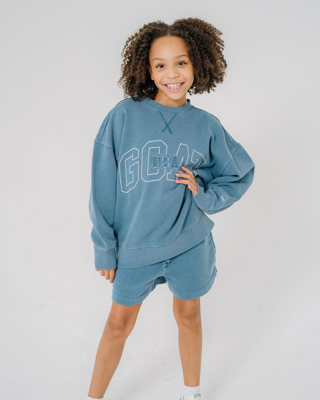 Girl wearing slate colored crewneck that reads "GOAT USA"#color_slate