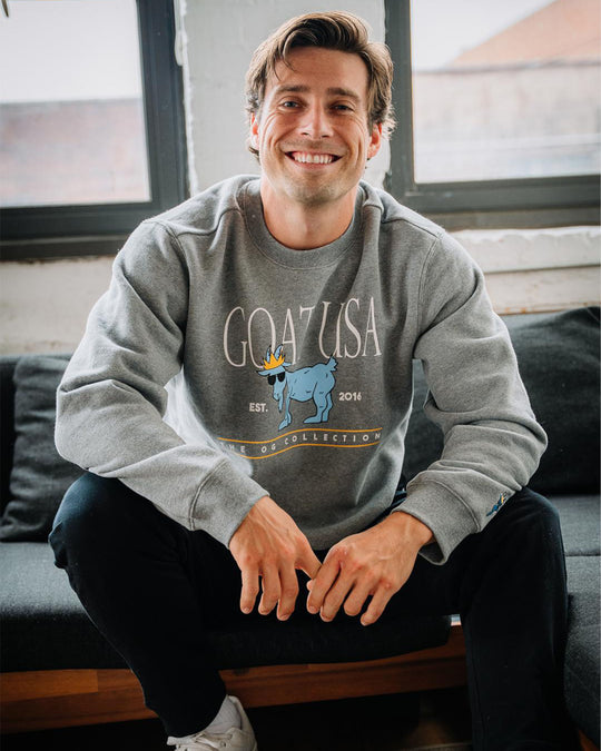 Model sitting on couch wearing gray crewneck#color_gray