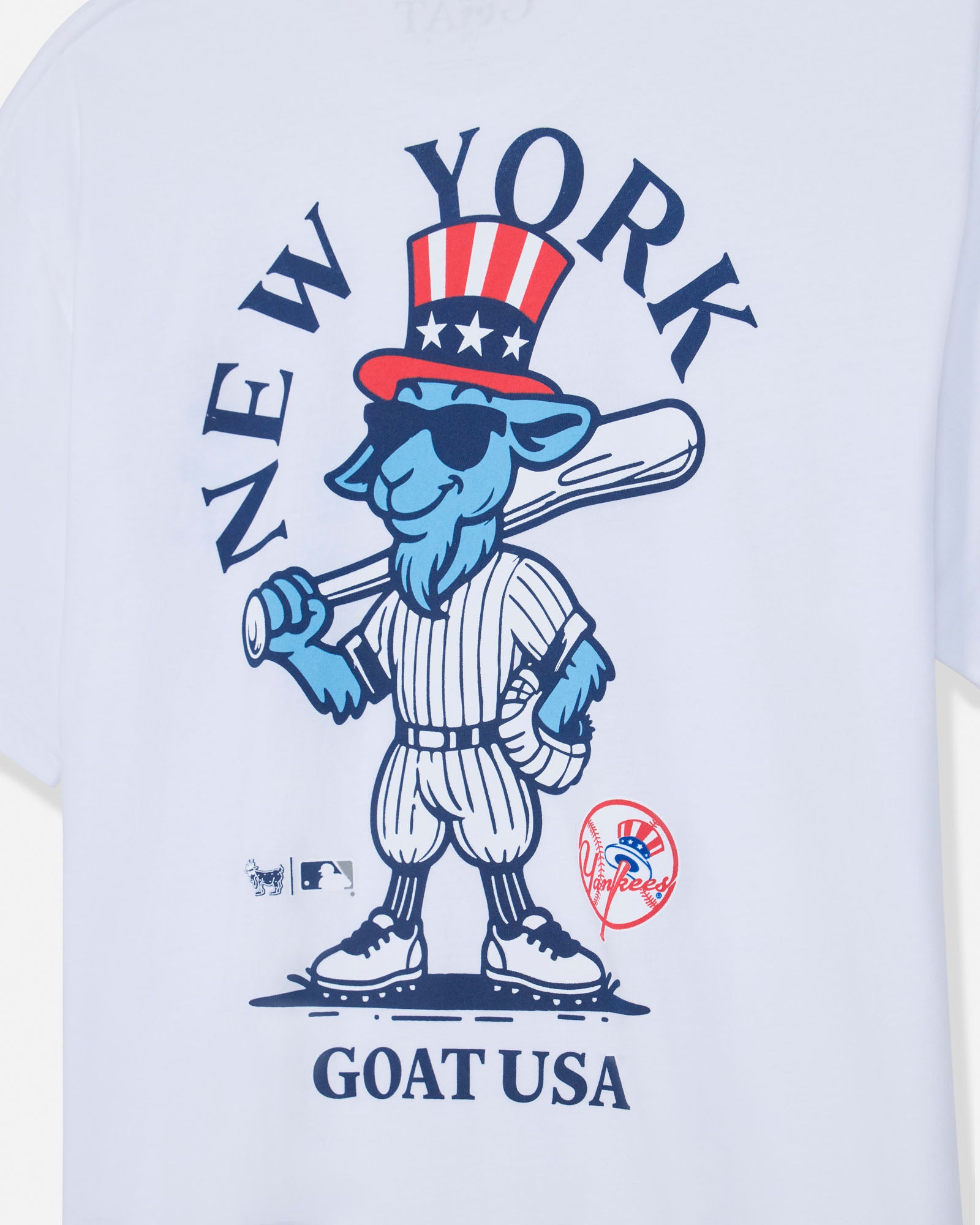 White short-sleeve t-shirt featuring a blue cartoon goat mascot in a baseball uniform with a red, white, and blue top hat. The graphic includes the text 'NEW YORK' arched above and 'GOAT USA' below, with MLB and New York Yankees logos near the bottom.#color_white