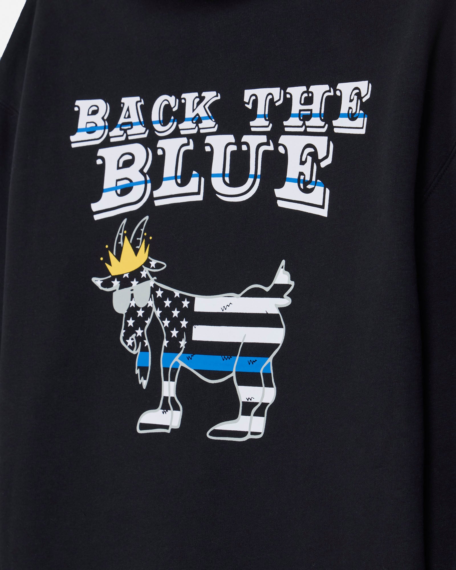 Close-up of a black sweatshirt featuring a graphic print that reads 'BACK THE BLUE' above a stylized goat filled with a U.S.