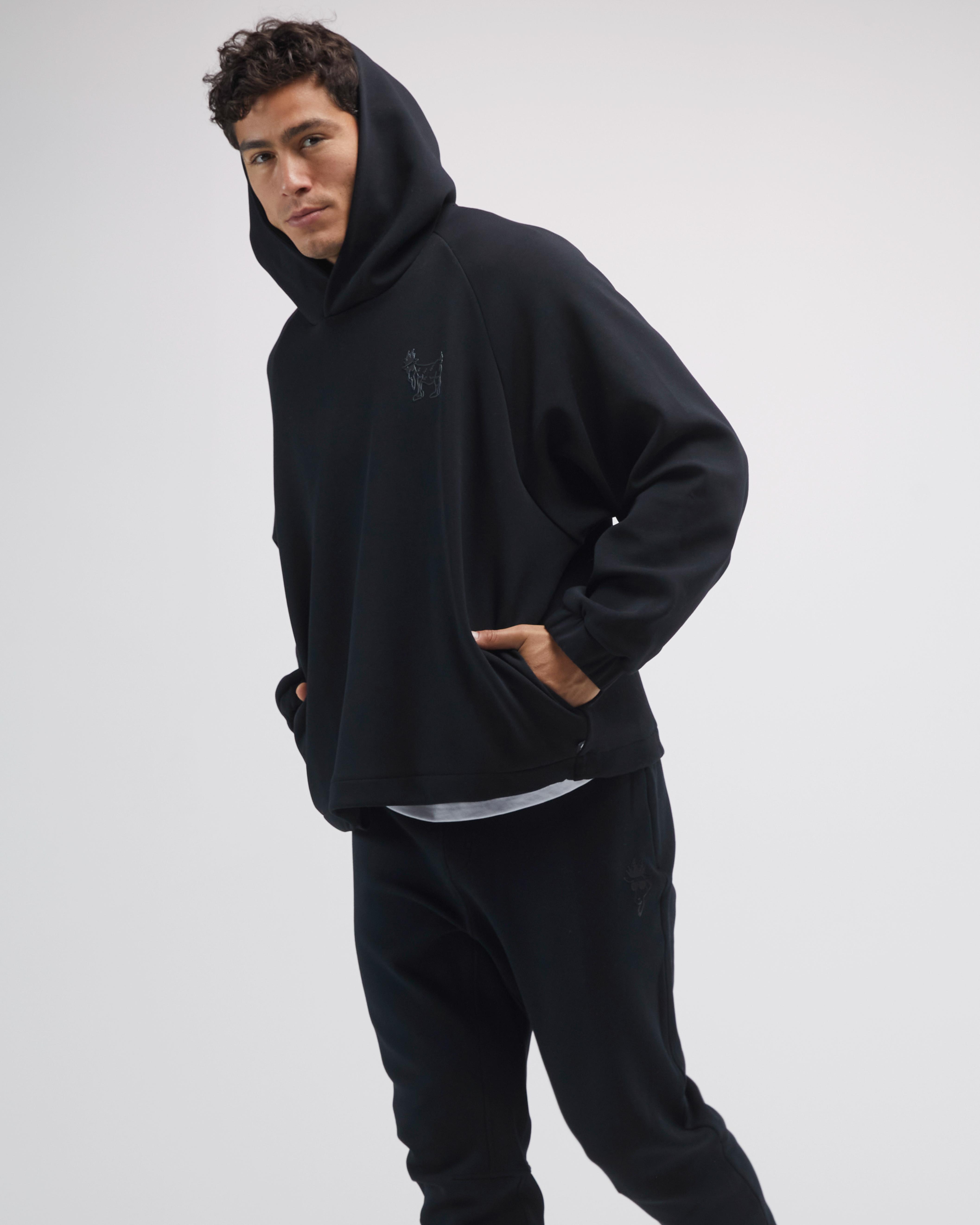 Person wearing a black hoodie and pants on a light gray background#color_black