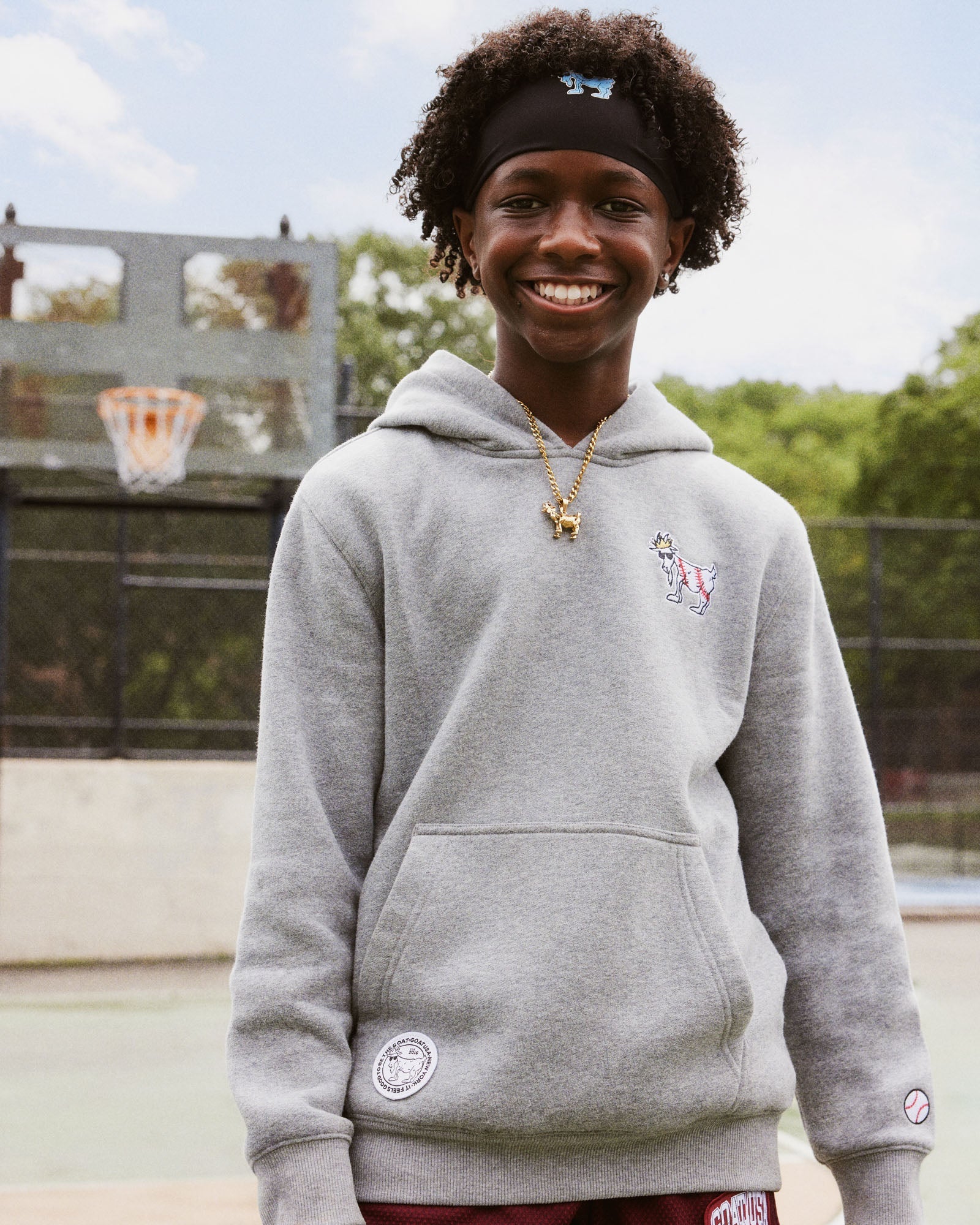 Person wearing a gray hoodie with a small design on a basketball court
