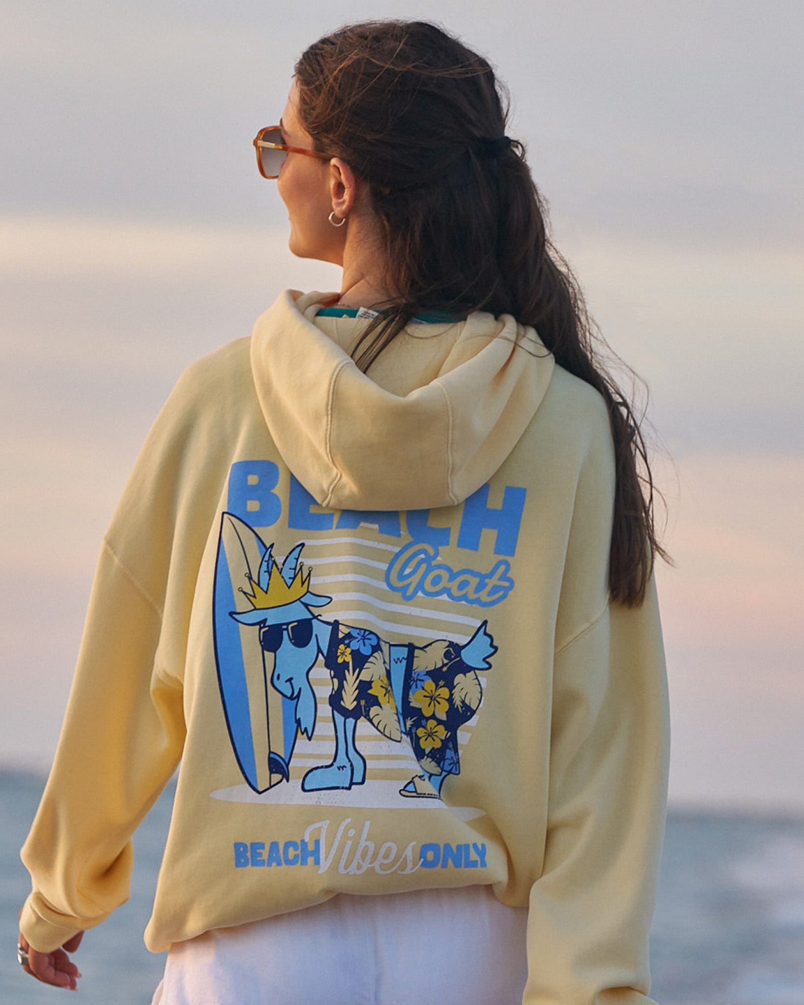 Woman in yellow hoodie on the beach at sundown