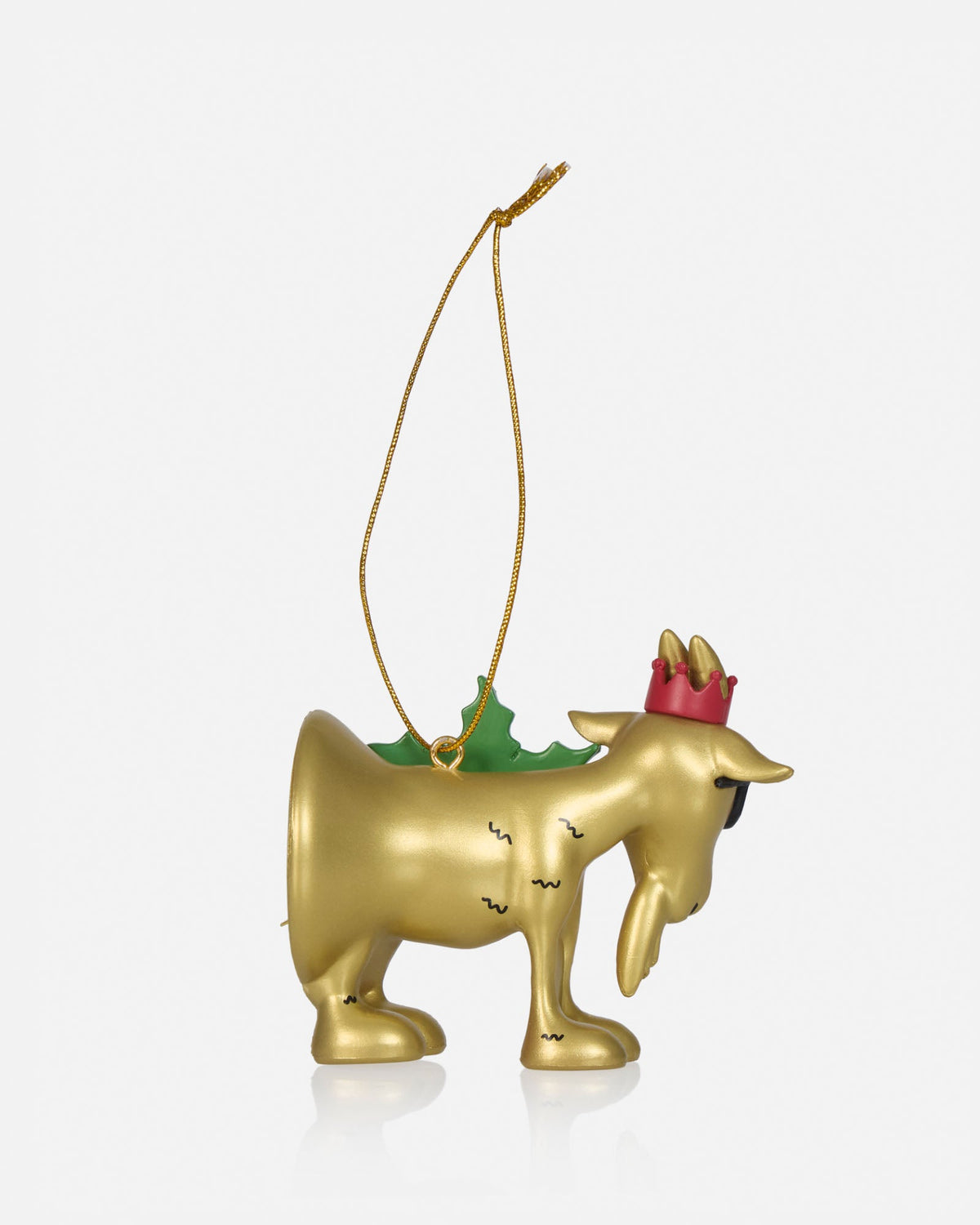 A gold Christmas ornament shaped like a goat wearing a red crown, with a green pine tree on its back and a gold hanging string, shown against a light gray background.