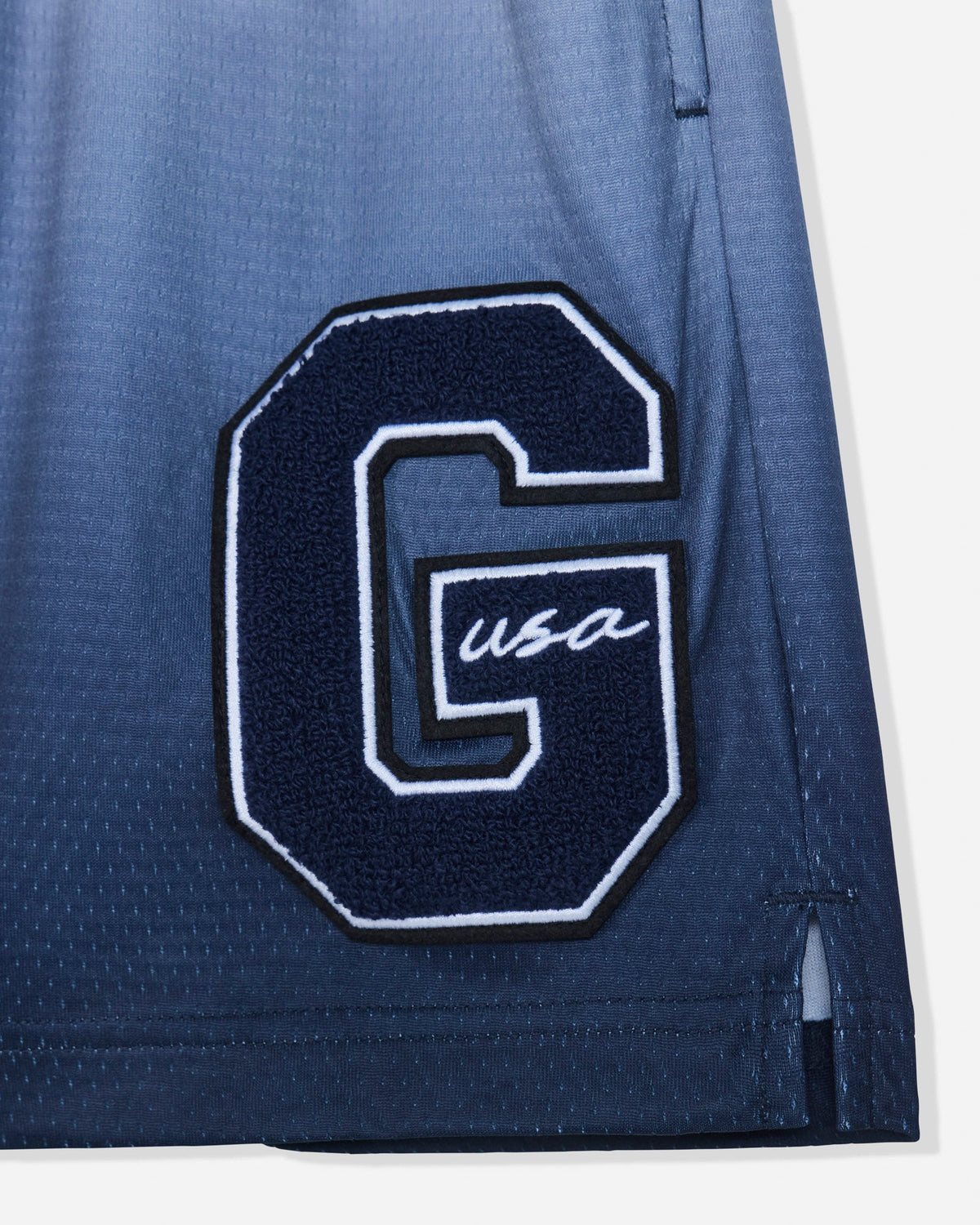 Close-up of 'G'-patch on navy fade mesh shorts