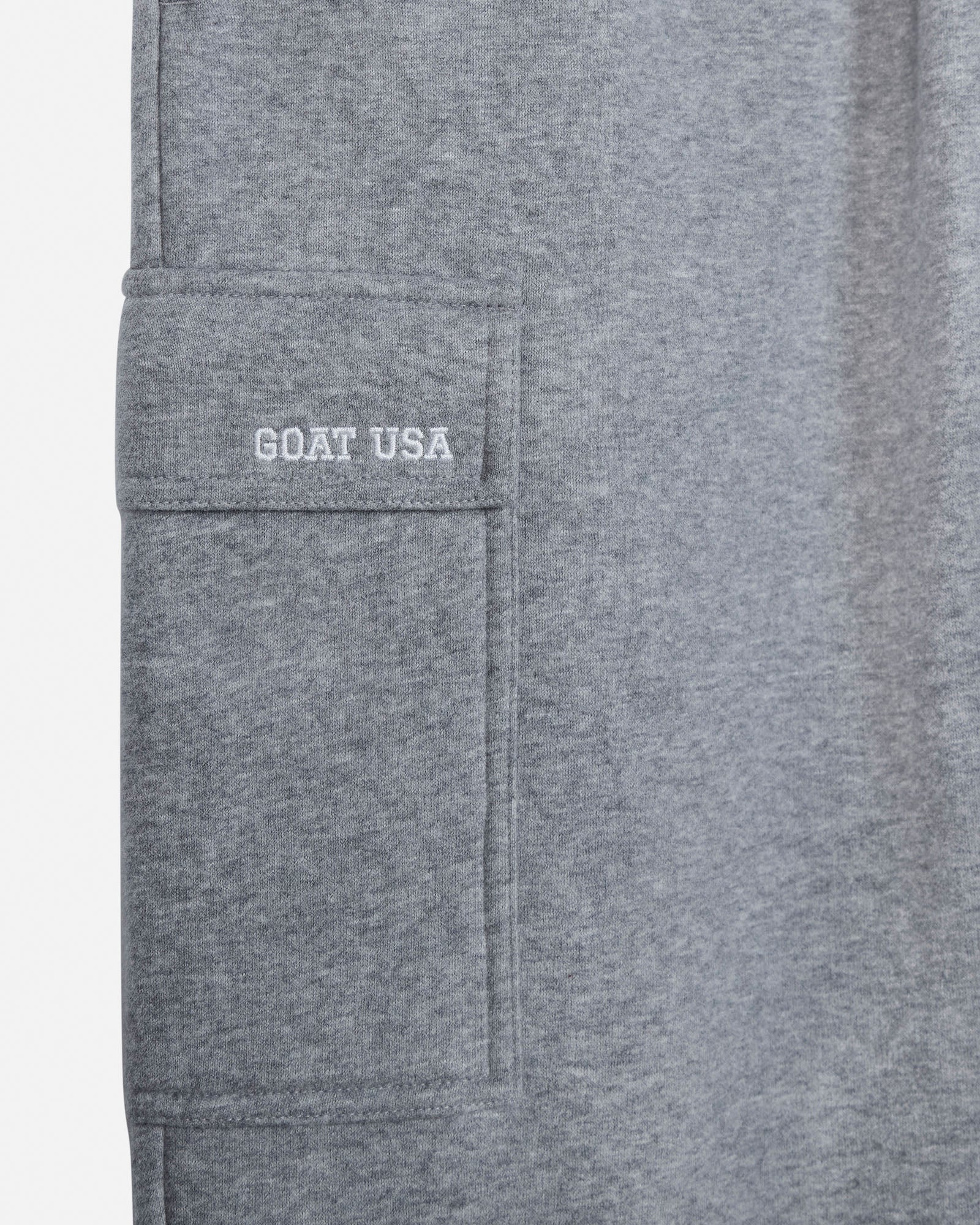Close-up of a heather gray fabric garment showing a side pocket with 'GOAT USA' embroidered in white on the pocket flap.#color_gray-heather
