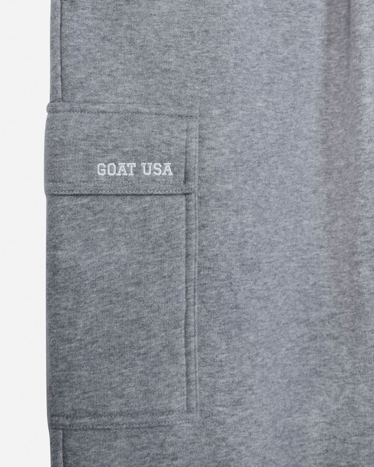 Close-up of a heather gray fabric garment showing a side pocket with 'GOAT USA' embroidered in white on the pocket flap.