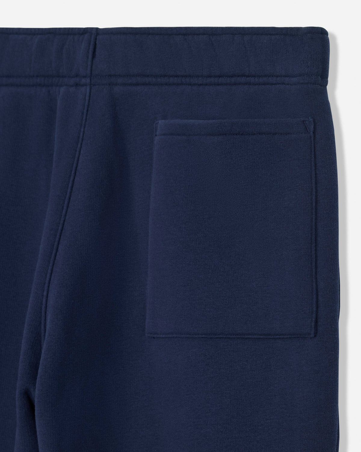 Close-up of navy blue sweatpants showing the waistband and a side pocket.