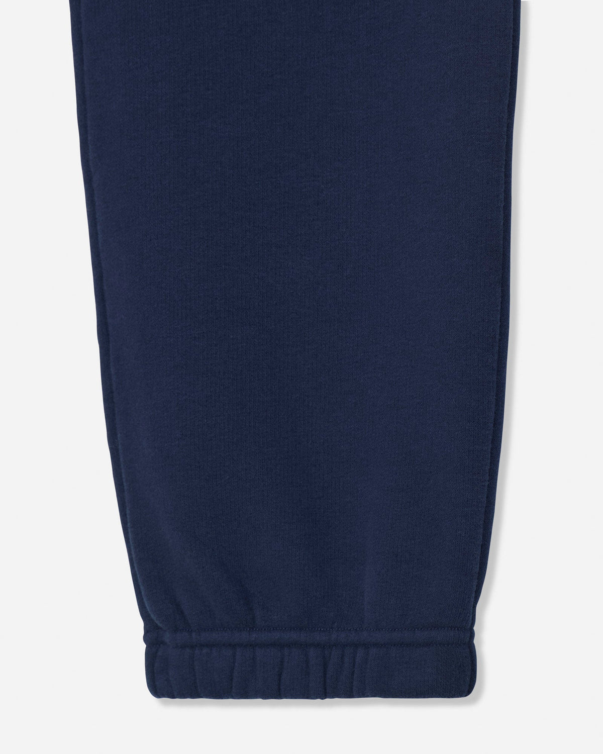 Close-up of a navy blue sweatpants leg showing the ribbed elastic cuff on a light gray background.