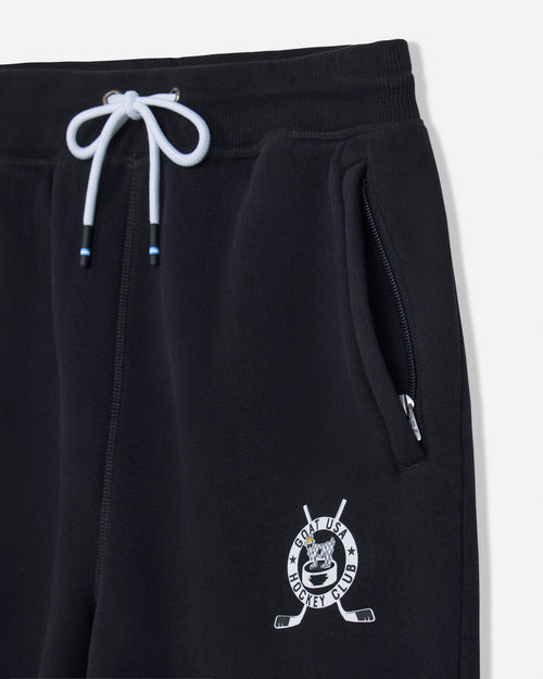 Close-up of black sweatpants with a white drawstring, side zip pocket, and a white hockey-themed crest logo near the lower left leg.