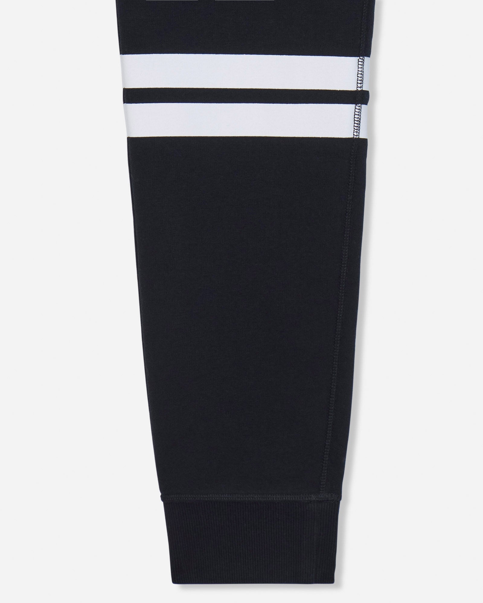 A close-up of a black garment leg with two horizontal white stripes near the upper section, shown against a light gray background.