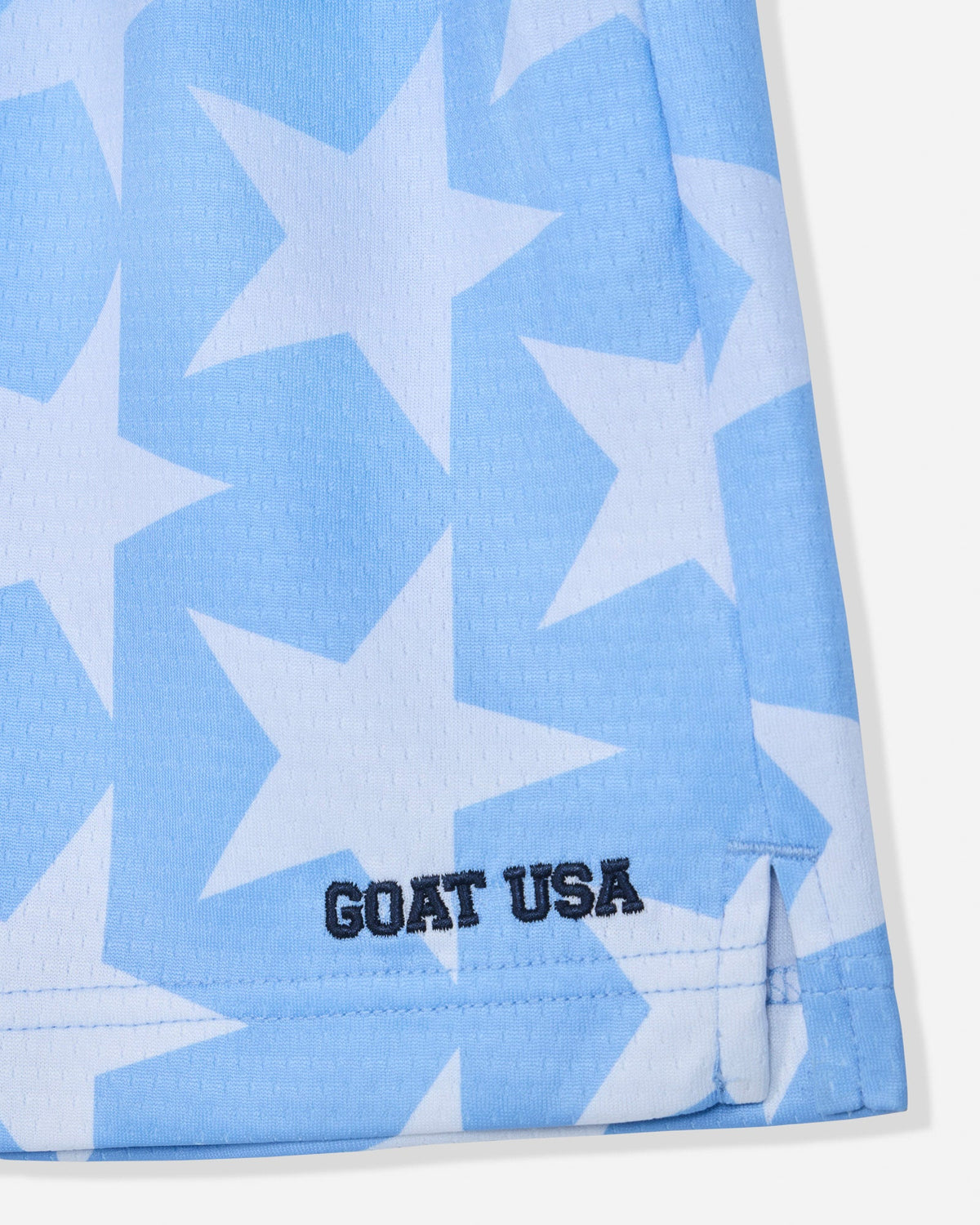 Close-up of carolina blue mesh shorts with a star pattern with stitched 'GOAT USA' text