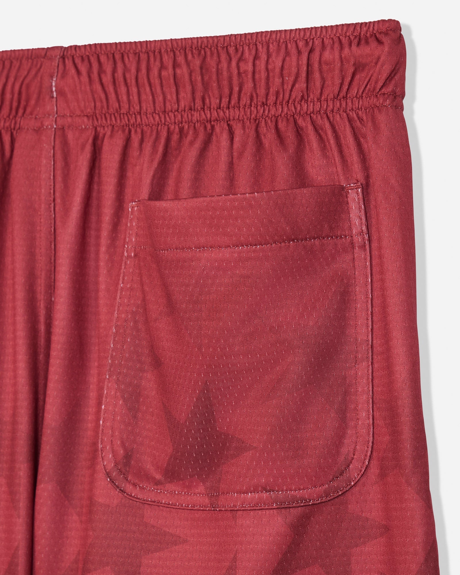 Close-up of back pocket on red mesh shorts with a star pattern#color_tomato