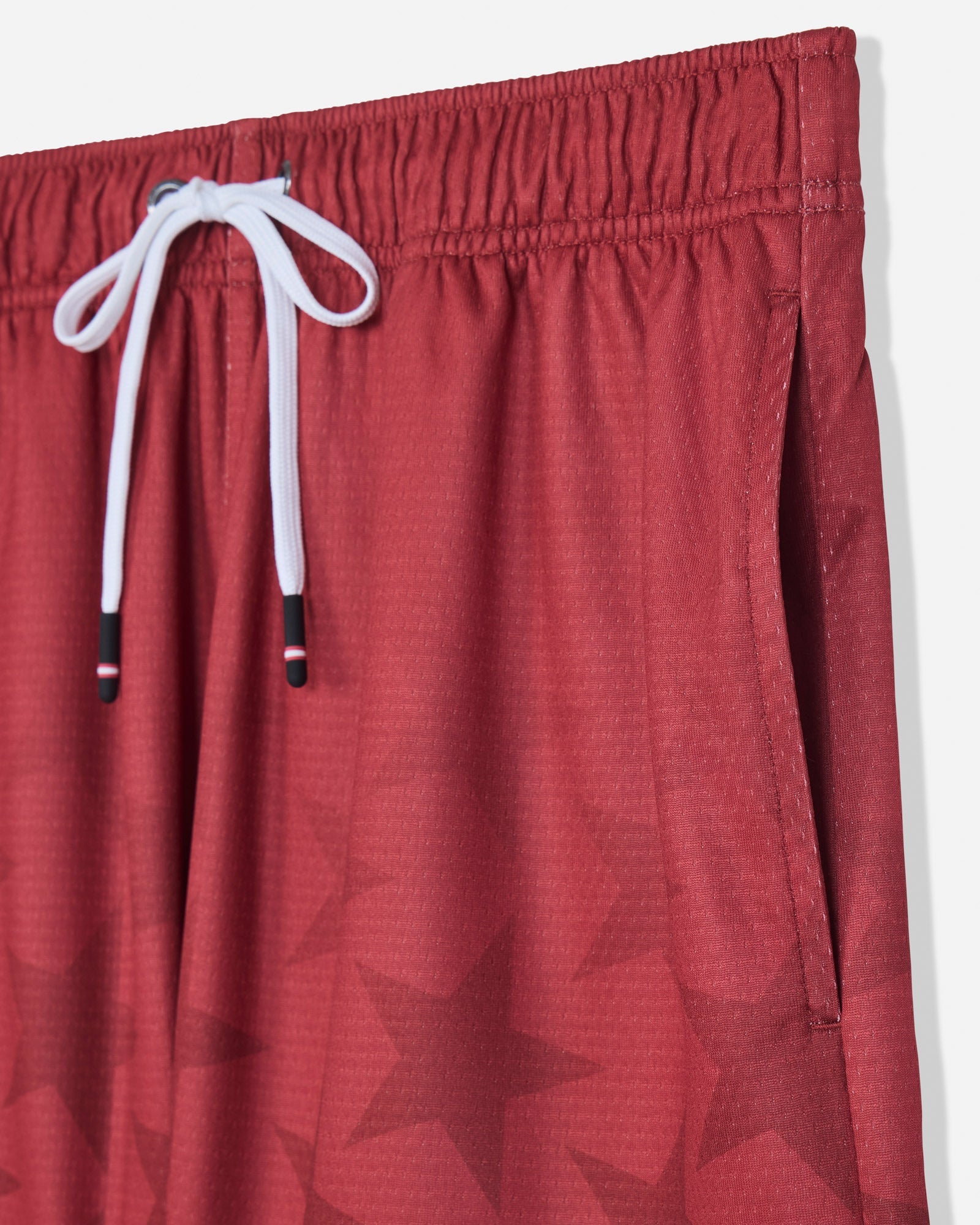 Close-up of pocket of red mesh shorts with a star pattern#color_tomato