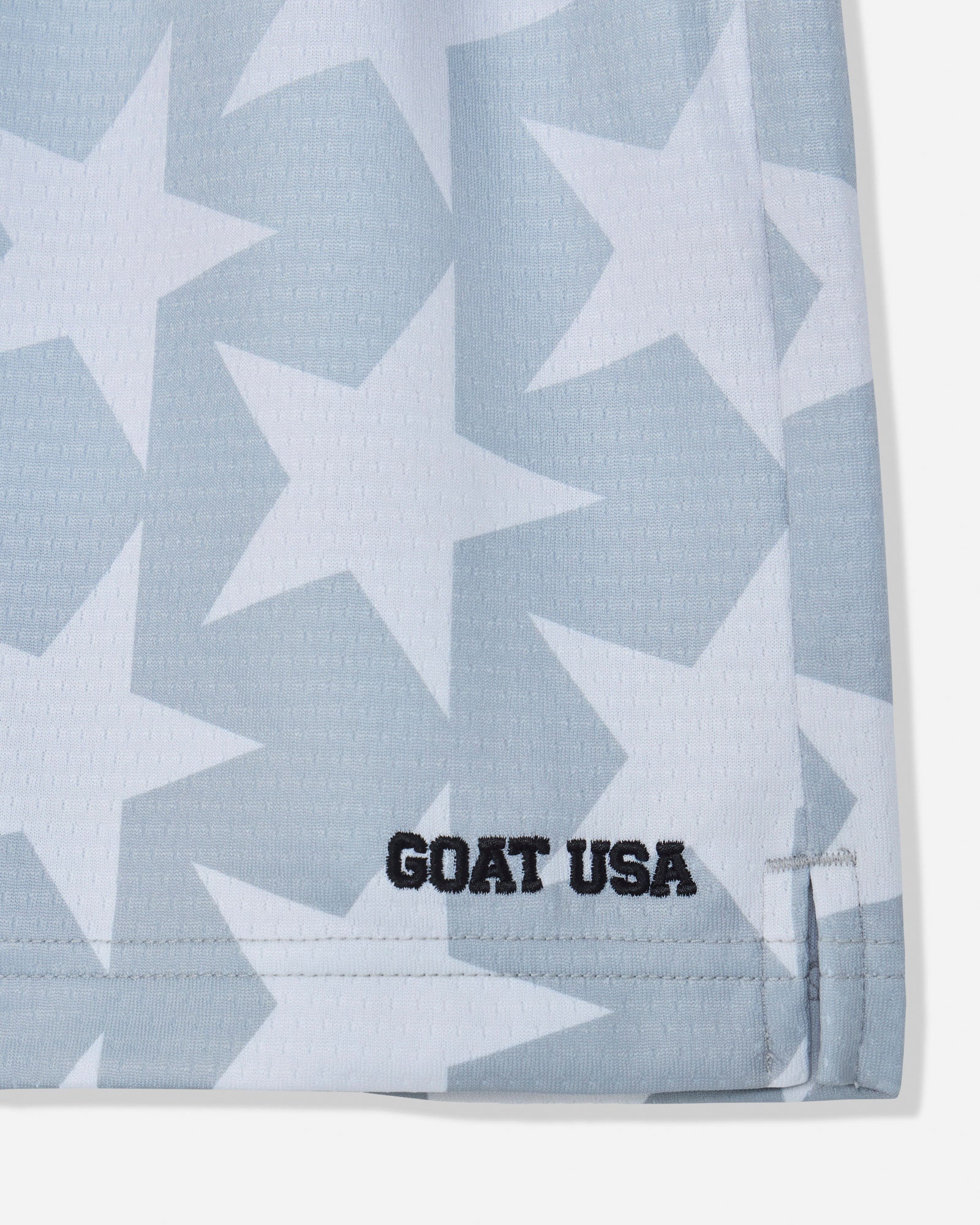 Close-up of gray mesh shorts with a star pattern and stitched 'GOAT USA' text#color_gray