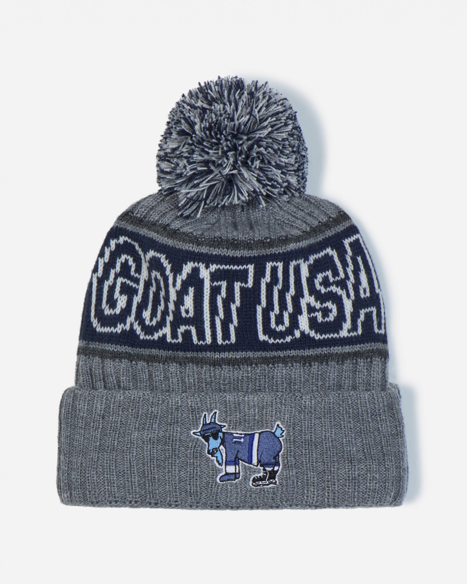 A gray and navy blue knit beanie with a gray pom-pom, featuring 'GOAT USA' in white lettering on a navy band and a small goat mascot patch on the front cuff.