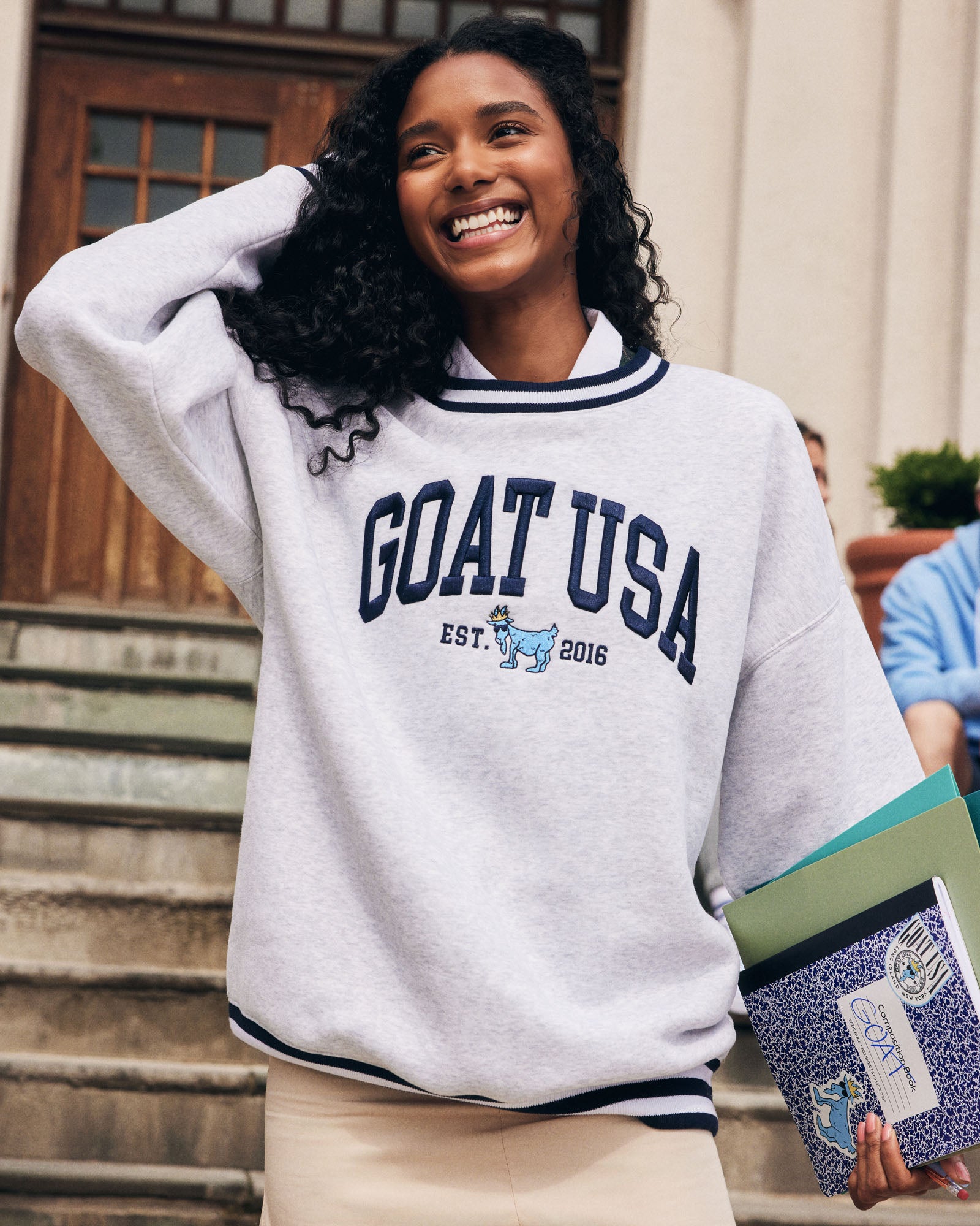 Woman wearing a 'GOAT USA' sweatshirt standing outdoors.