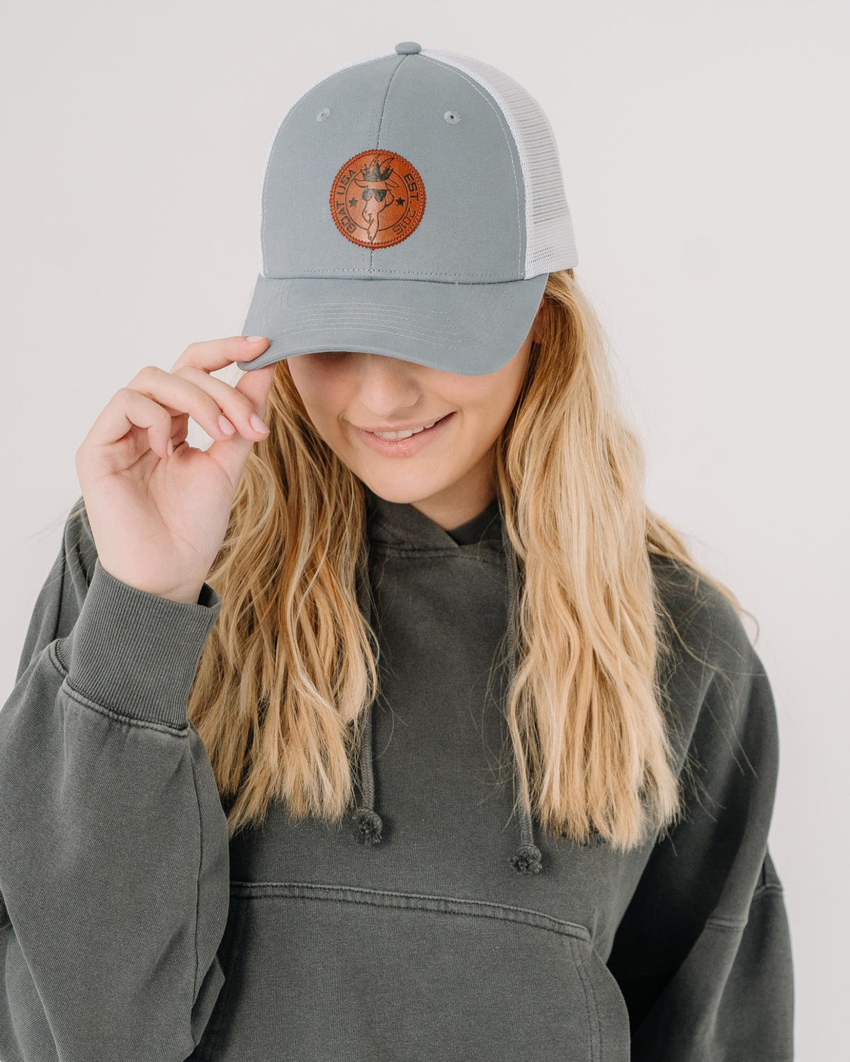 Girl wearing gray hat with white mesh and brown leather patch