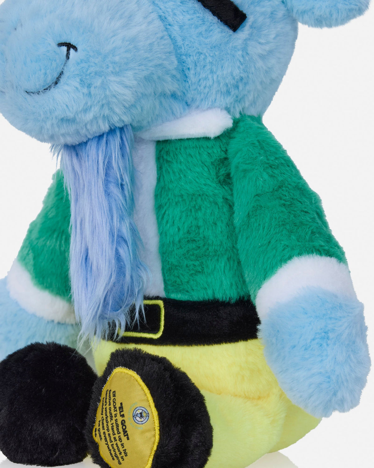 A close-up of a plush toy wearing a green and white outfit with a black belt, light blue body, and yellow pants, shown against a plain light background.