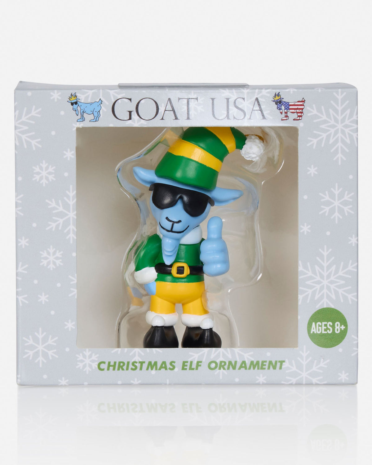 Goat USA Christmas Elf Ornament in its original retail packaging. The ornament features a blue goat dressed as a Christmas elf with a green and yellow striped hat, green outfit, yellow pants, and black sunglasses, giving a thumbs-up.