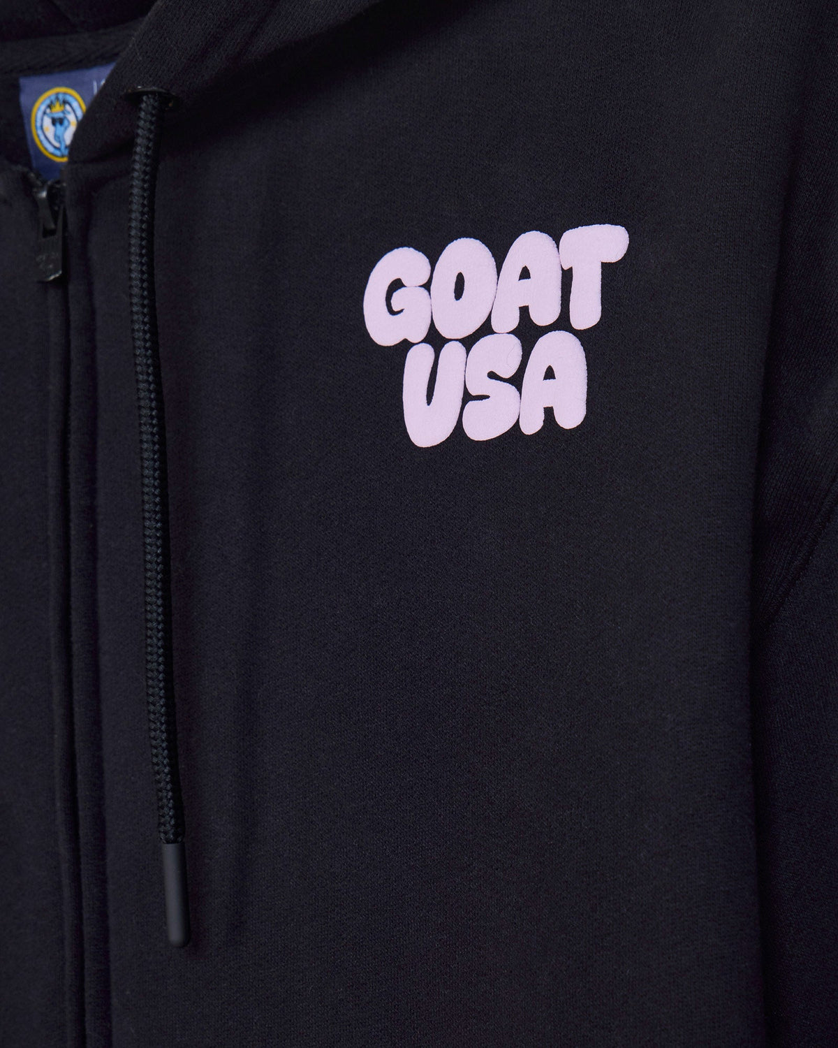 Close-up of front of black hoodie with 'GOAT USA' left-chest logo text