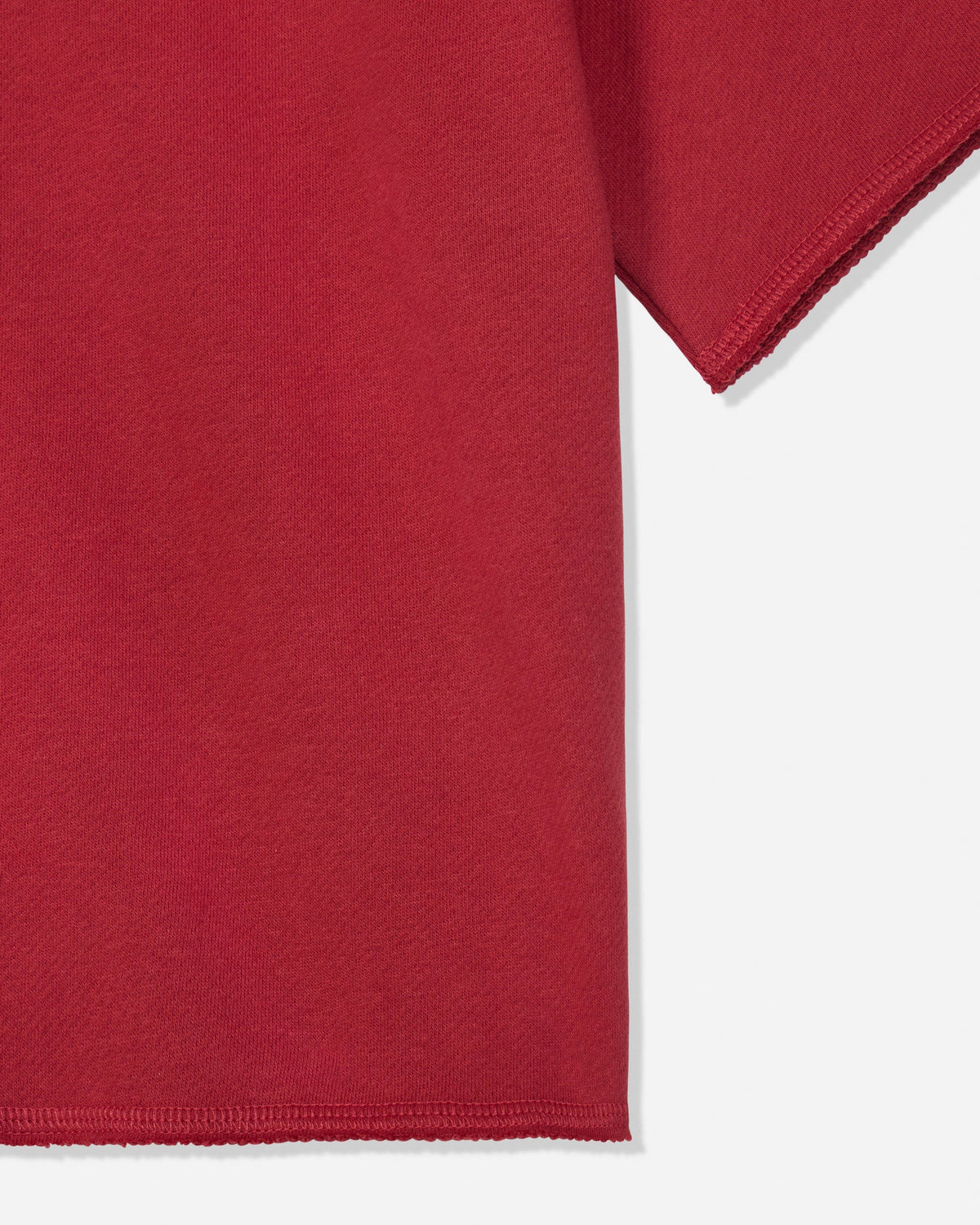 Close-up of a red short-sleeve garment showing the sleeve and hem against a light gray background.