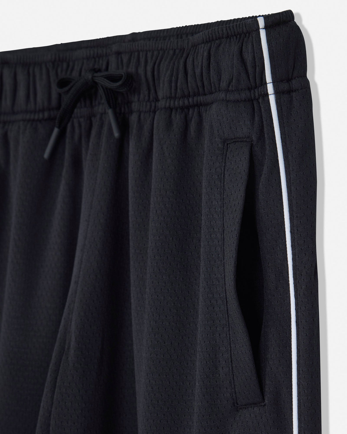 Close-up of black athletic shorts with a textured mesh fabric, featuring an elastic drawstring waistband and a white side stripe.