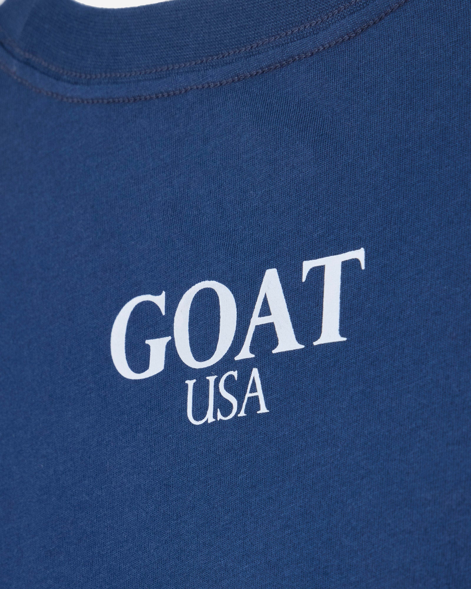 Close up of back of blue oversized crop top with 'GOAT USA' text#color_moonlite-ocean