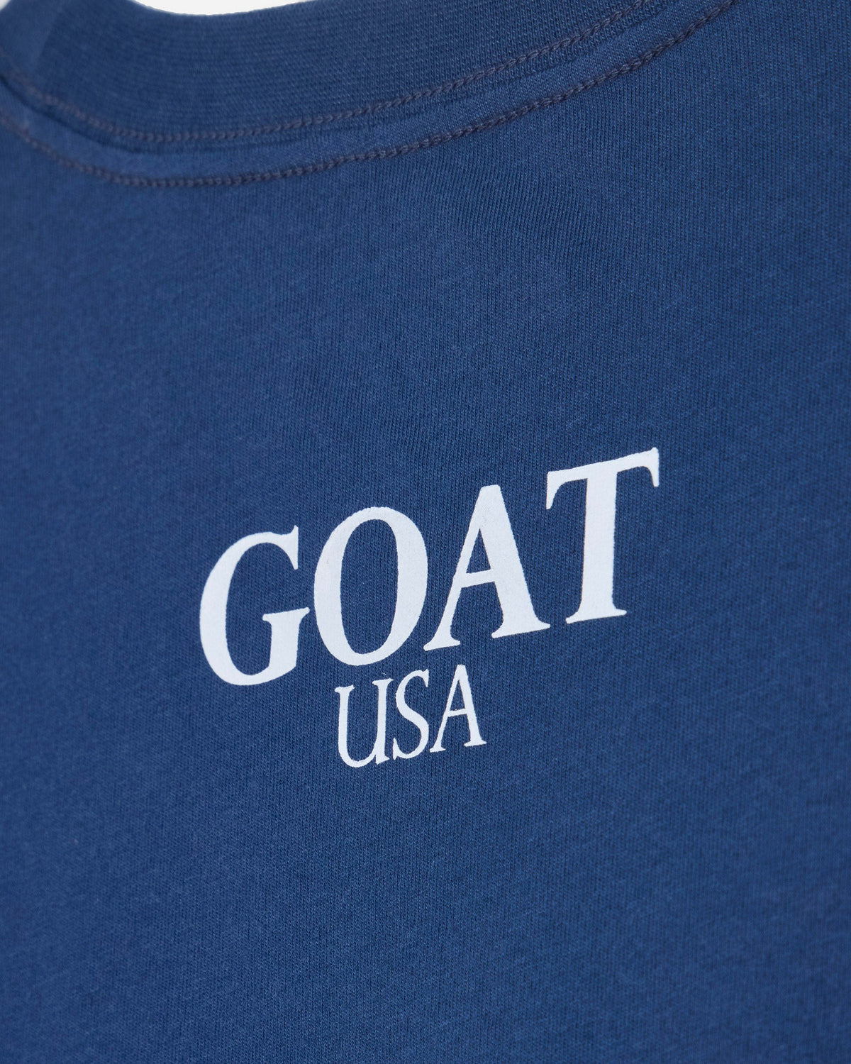 Close up of back of blue oversized crop top with 'GOAT USA' text