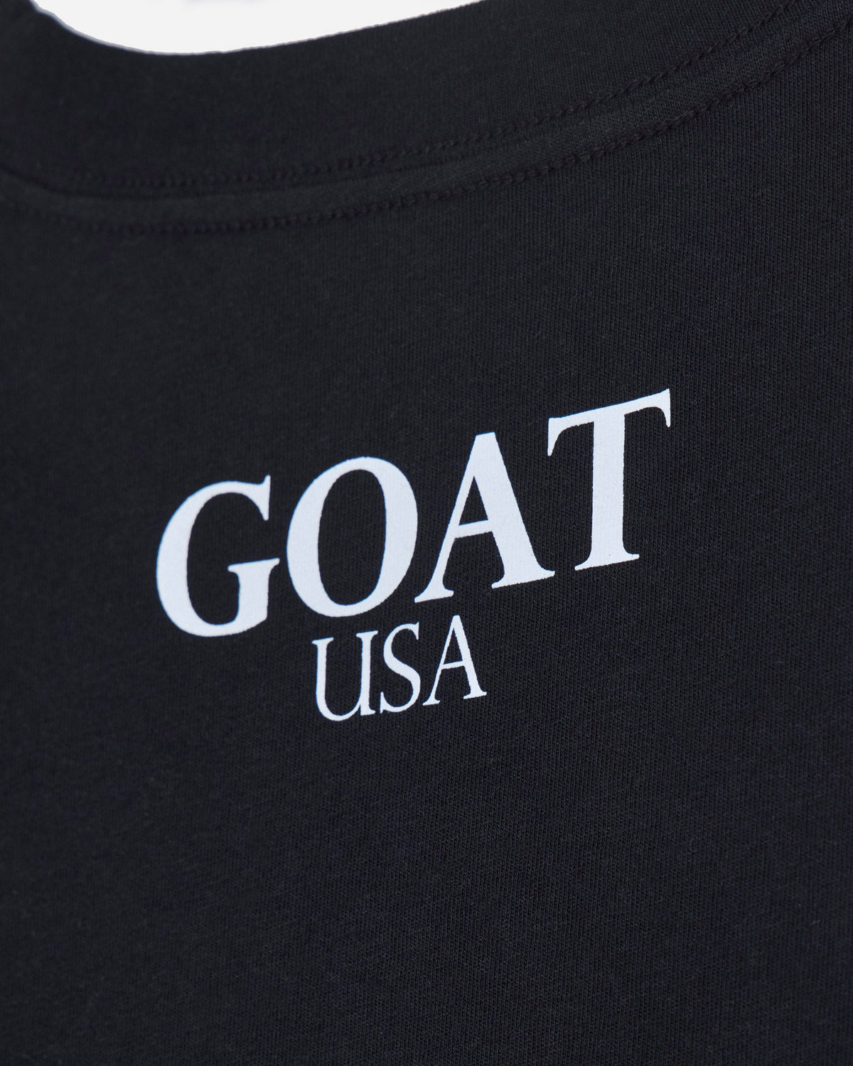 Close up of back of black oversized crop top with 'GOAT USA' text