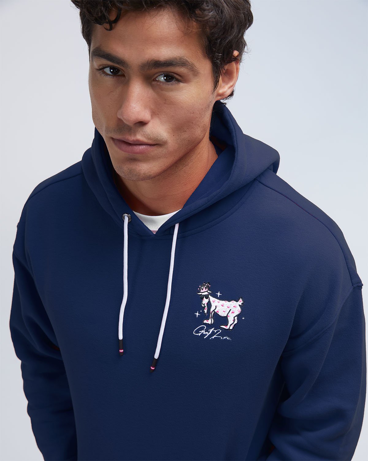 Man wearing a navy blue hoodie with a logo on a light gray background