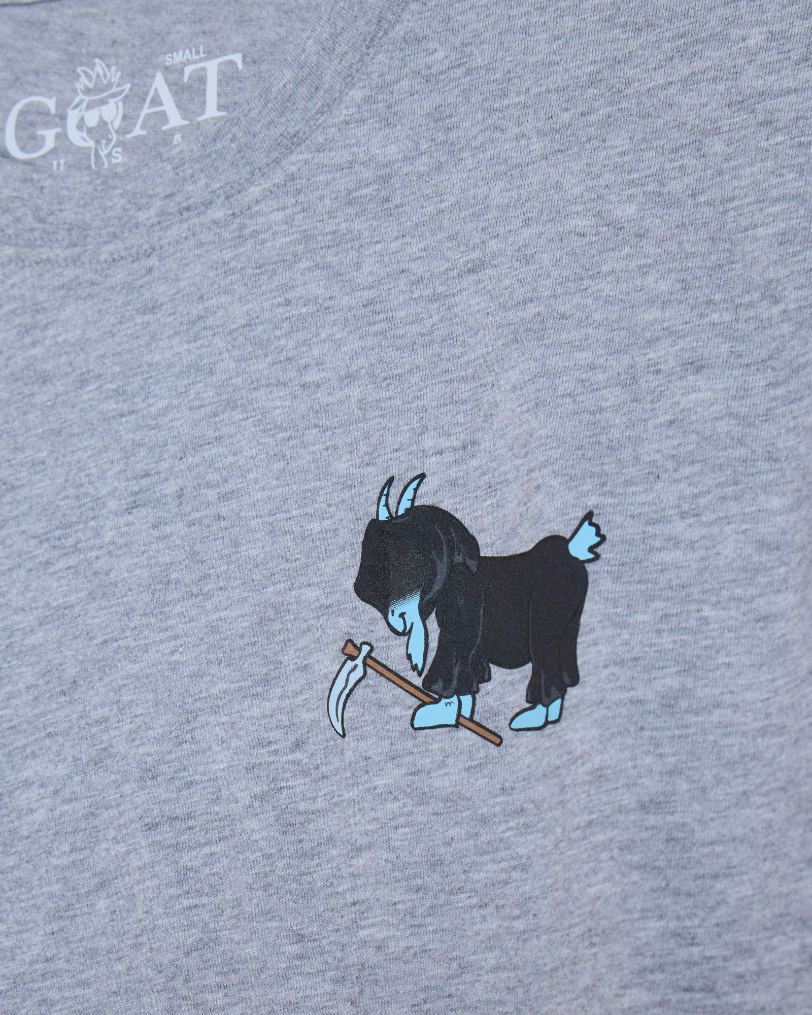 Close-up of a heather gray t-shirt featuring a graphic of a blue goat holding a scythe, with a white 'GOAT' brand logo printed in the upper left corner.
