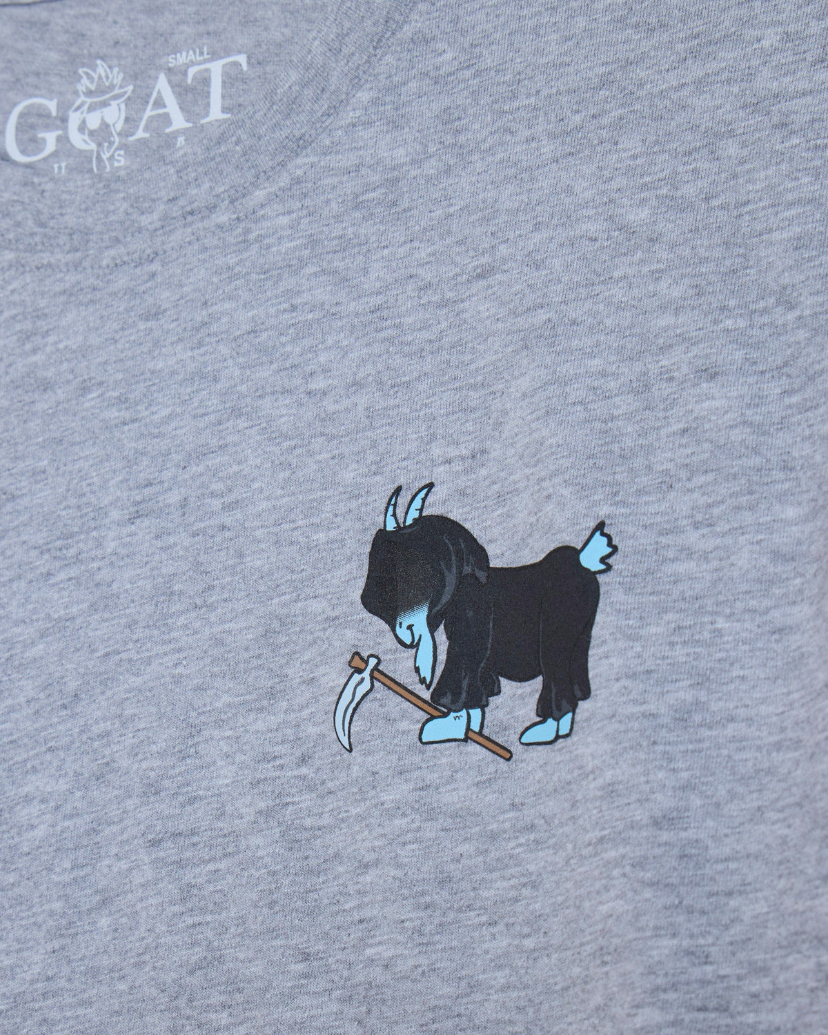 Close-up of a heather gray t-shirt featuring a graphic of a blue goat holding a scythe, with a white 'GOAT' brand logo printed in the upper left corner.