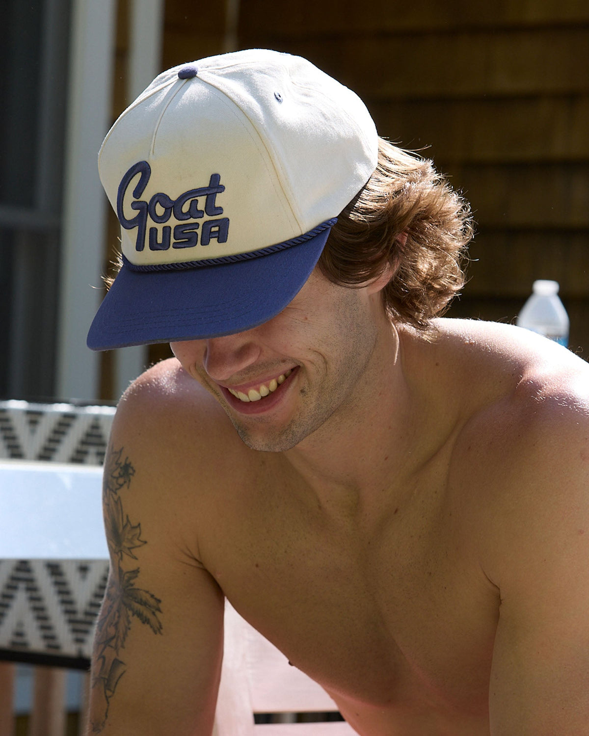 Man wearing a cap with 'Goat USA', sitting outdoors.