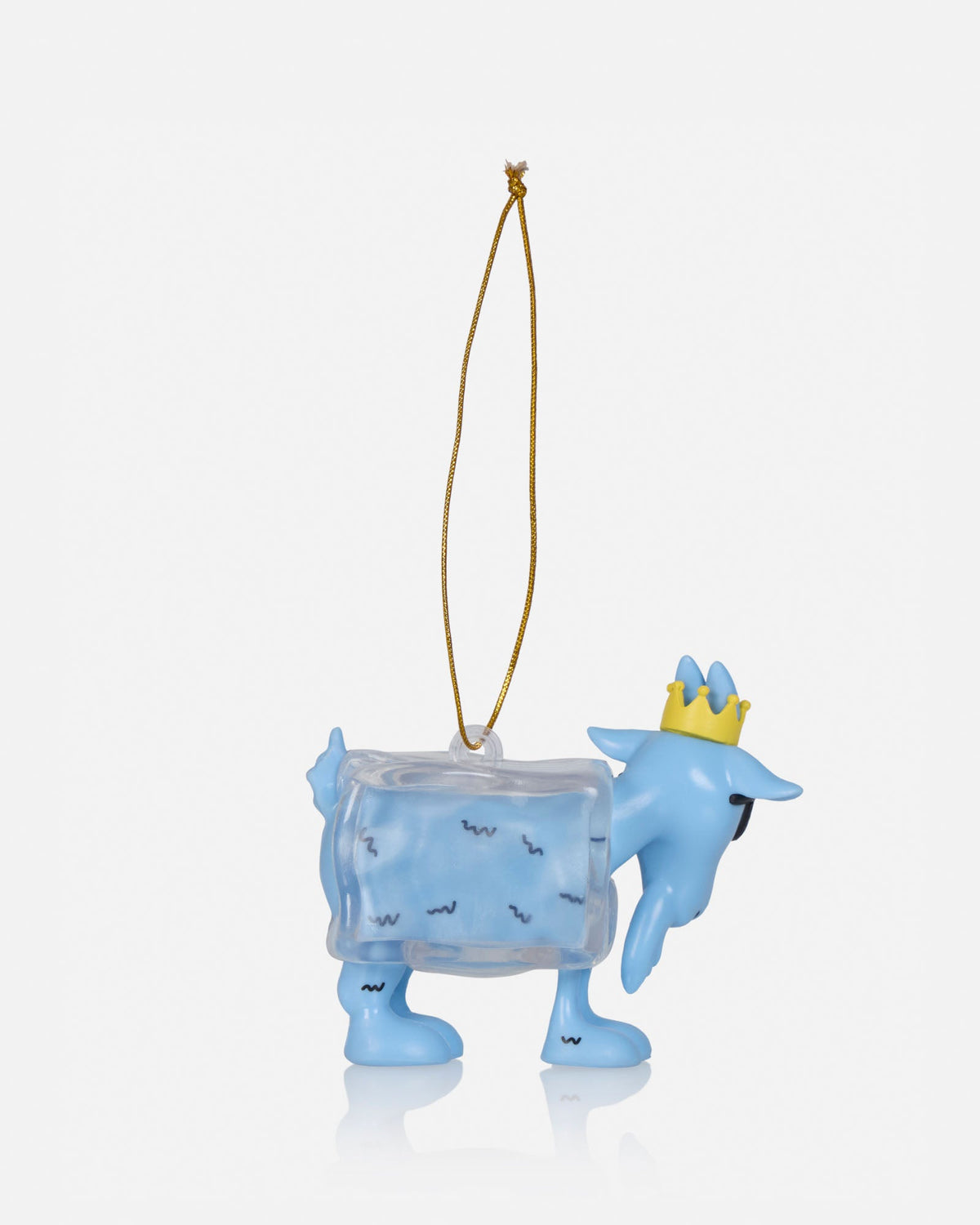 A light blue Christmas ornament shaped like a goat carrying a transparent ice cube, with a small gold crown on its head and a gold hanging string, shown on a light gray background.