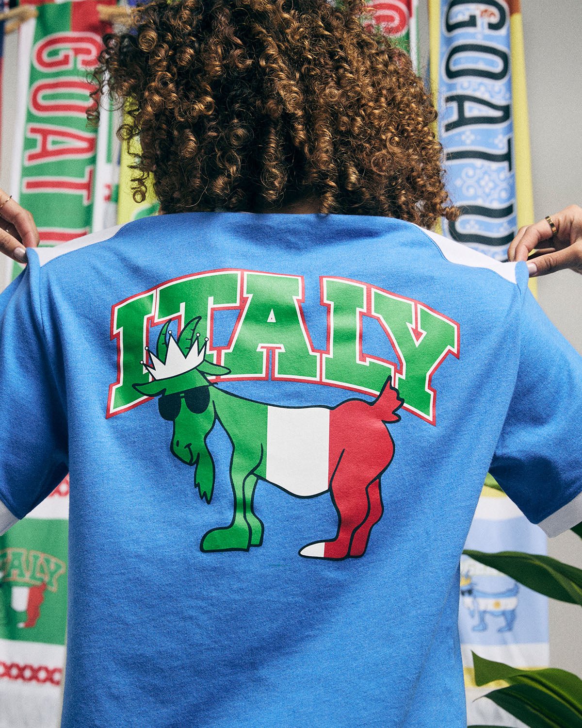 Blue t-shirt with 'ITALY' and flag design on the back, held by a person.